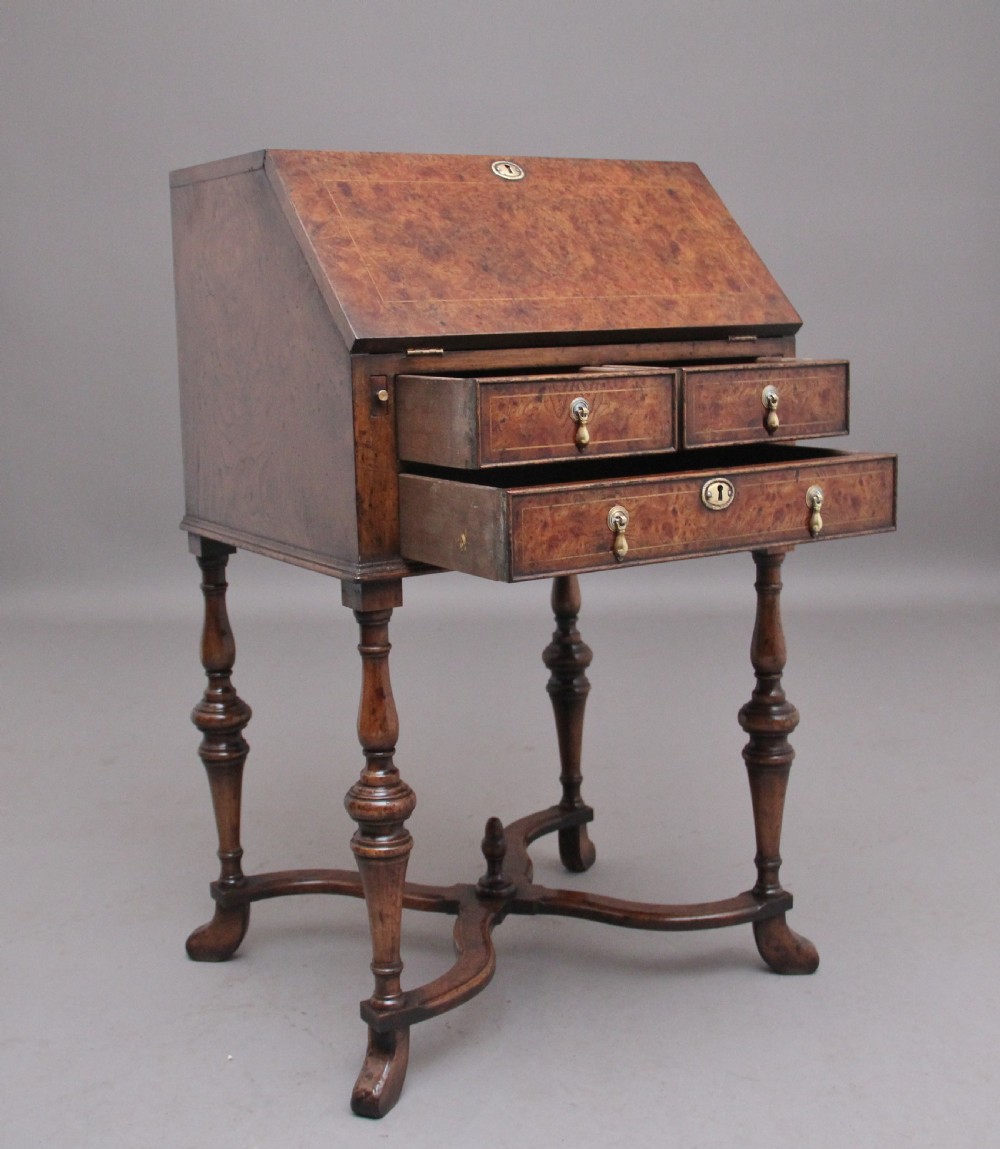 An early 20th-century walnut writing bureau on stand with a sloped fall front, lower drawers, and turned legs with a shaped cross-stretcher. View IX