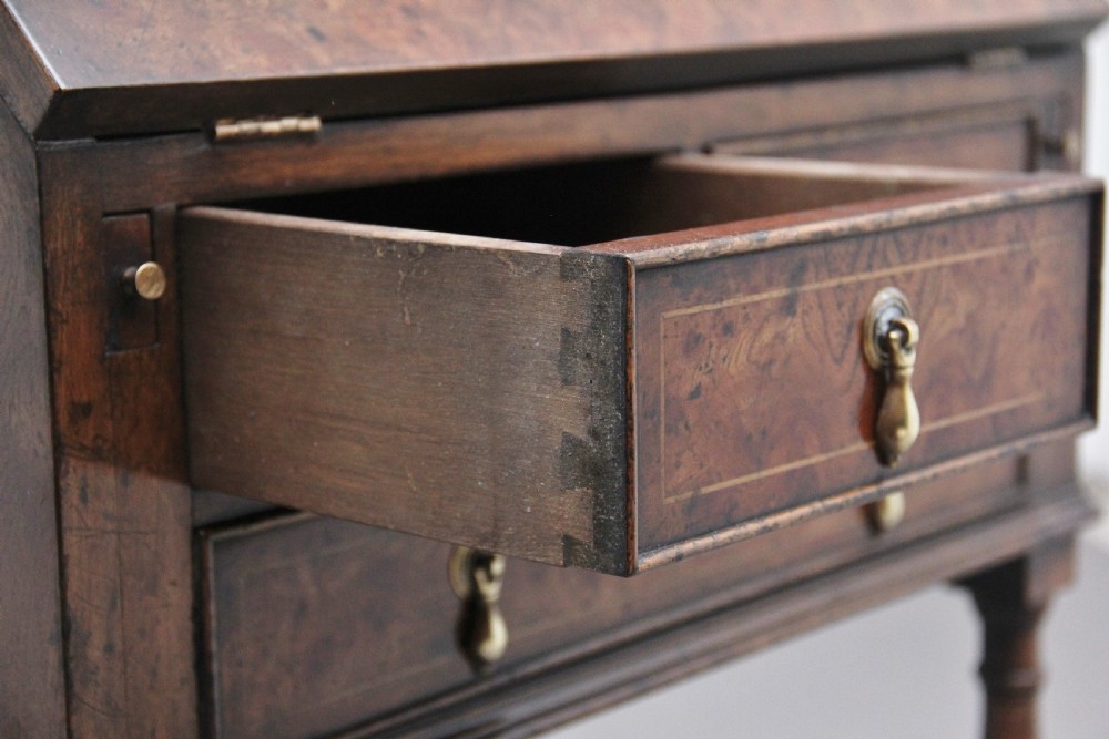 An early 20th-century walnut writing bureau on stand with a sloped fall front, lower drawers, and turned legs with a shaped cross-stretcher. View XIII