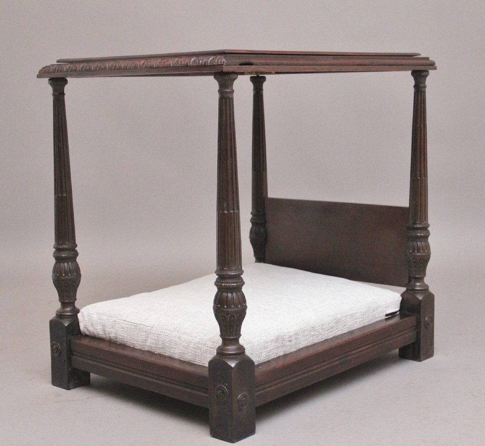 A nineteenth-century mahogany four-poster dog bed featuring carved reeded posts, a moulded canopy frame, and a neutral fabric cushion. View IV