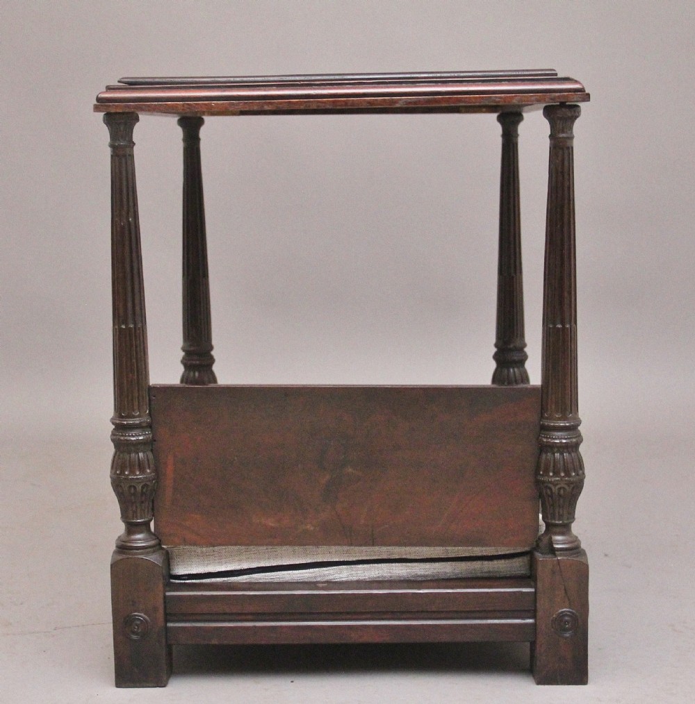 A nineteenth-century mahogany four-poster dog bed featuring carved reeded posts, a moulded canopy frame, and a neutral fabric cushion. View VI