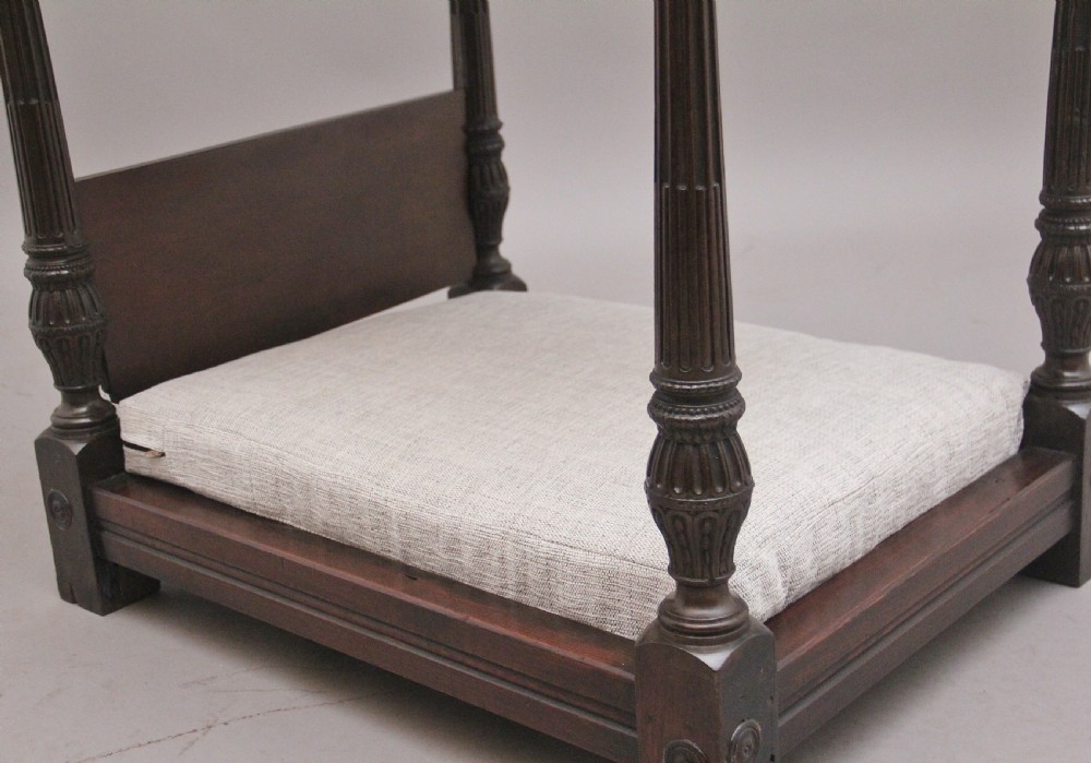 A nineteenth-century mahogany four-poster dog bed featuring carved reeded posts, a moulded canopy frame, and a neutral fabric cushion. View XI