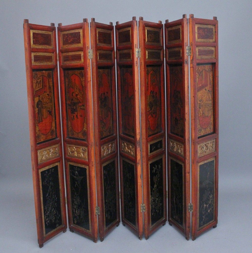 An early 20th-century seven-panel Chinese folding screen featuring crimson and black lacquered sections decorated with hand-painted figures and gilded floral borders. View II