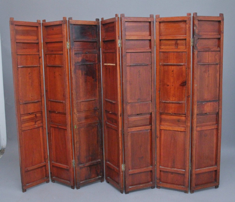 An early 20th-century seven-panel Chinese folding screen featuring crimson and black lacquered sections decorated with hand-painted figures and gilded floral borders. View III
