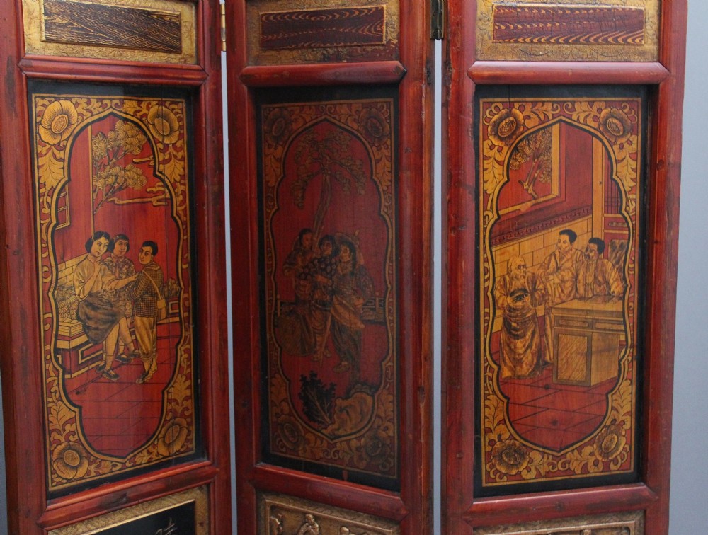 An early 20th-century seven-panel Chinese folding screen featuring crimson and black lacquered sections decorated with hand-painted figures and gilded floral borders. View V