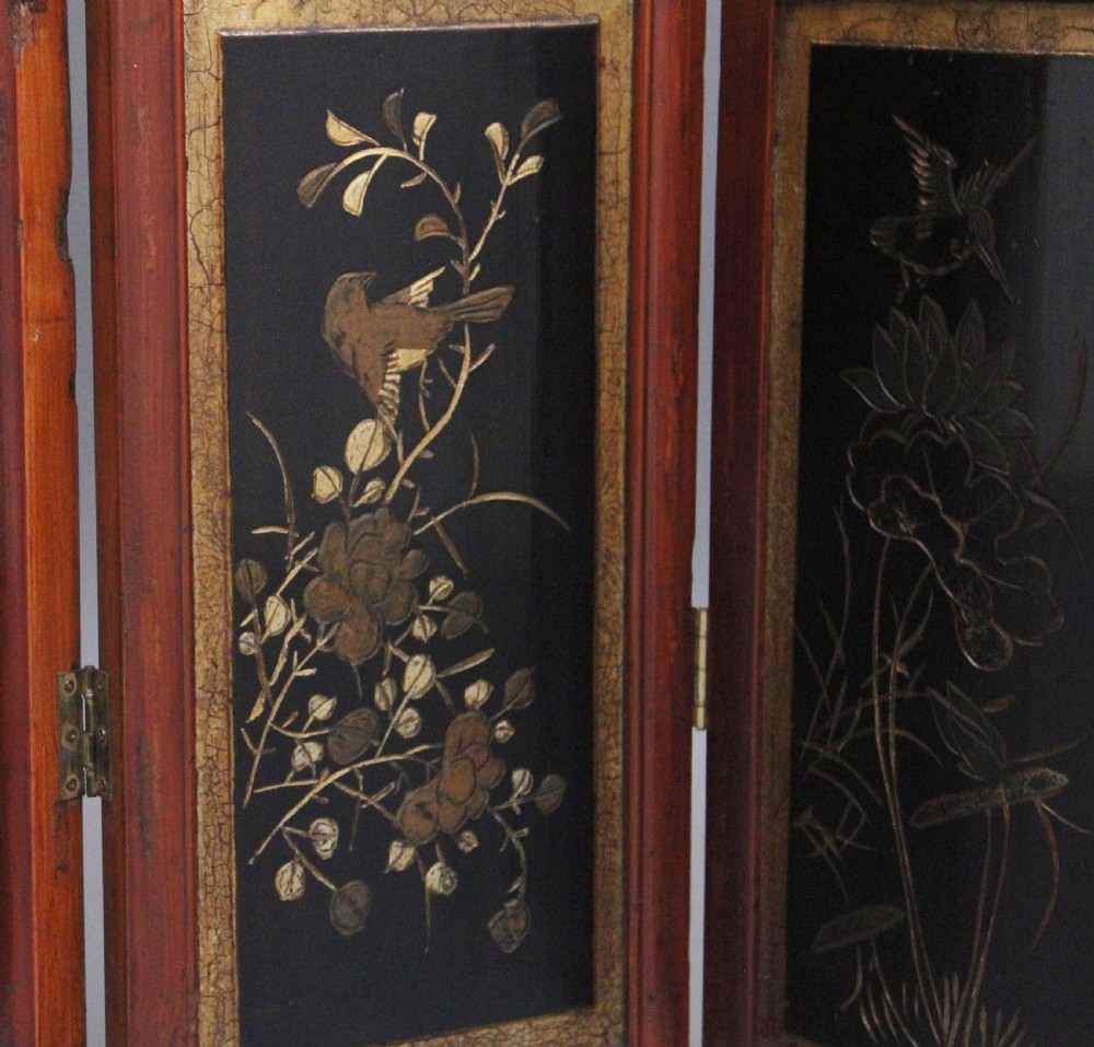 An early 20th-century seven-panel Chinese folding screen featuring crimson and black lacquered sections decorated with hand-painted figures and gilded floral borders. View XIV