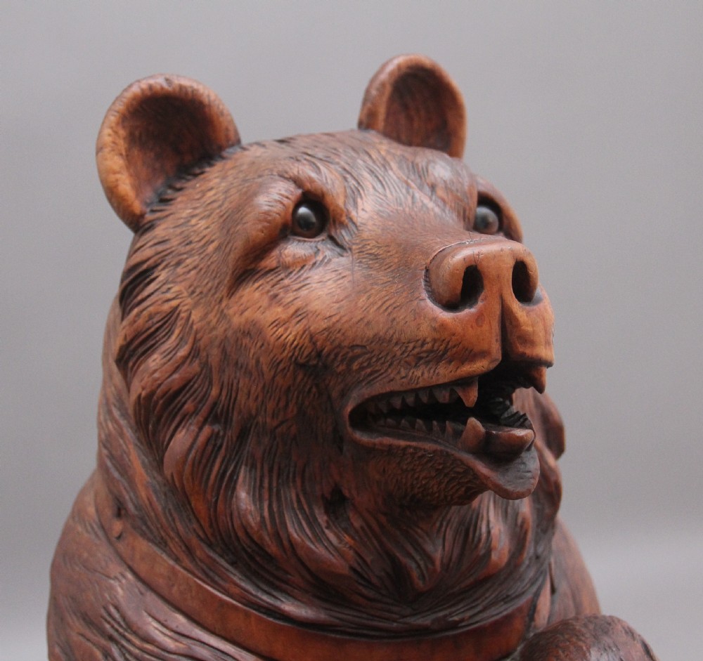 A 19th-century carved wooden Black Forest stick stand featuring a full-length standing bear holding an oval ring above a carved base with a metal drip tray. View VII