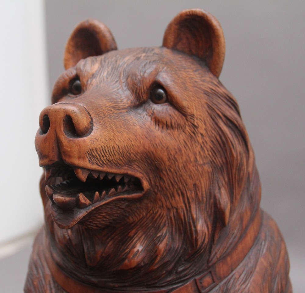 A 19th-century carved wooden Black Forest stick stand featuring a full-length standing bear holding an oval ring above a carved base with a metal drip tray. View VIII