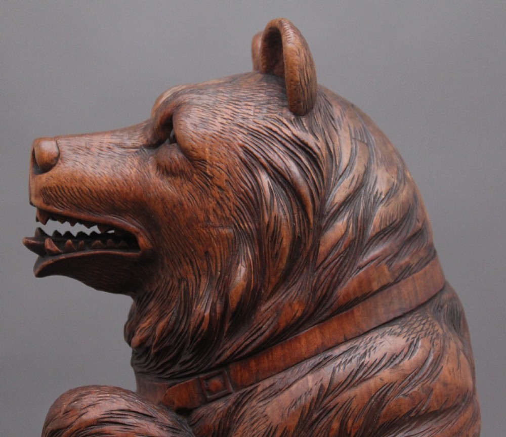 A 19th-century carved wooden Black Forest stick stand featuring a full-length standing bear holding an oval ring above a carved base with a metal drip tray. View IX