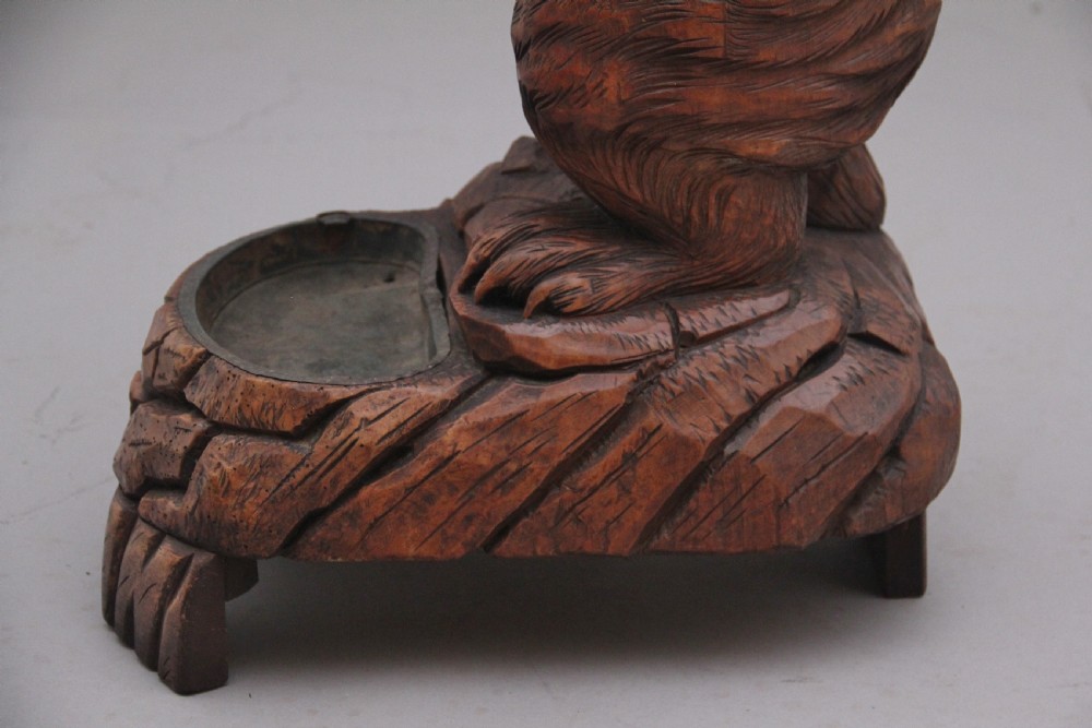 A 19th-century carved wooden Black Forest stick stand featuring a full-length standing bear holding an oval ring above a carved base with a metal drip tray. View XII