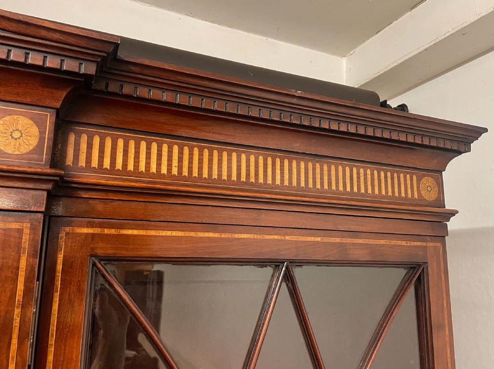 A 19th-century mahogany breakfront bookcase featuring a swan-neck pediment, geometrically glazed upper doors, and inlaid lower cupboard doors. View VIII