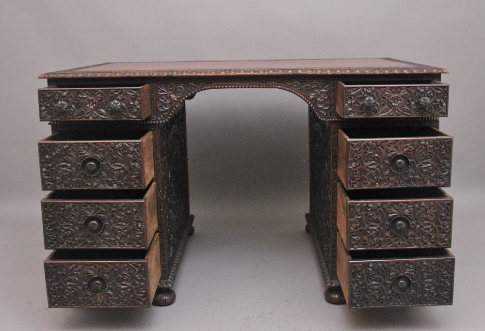 A dark wood double pedestal partners desk featuring intricate relief floral carvings across all drawers, side panels, and top borders. View II
