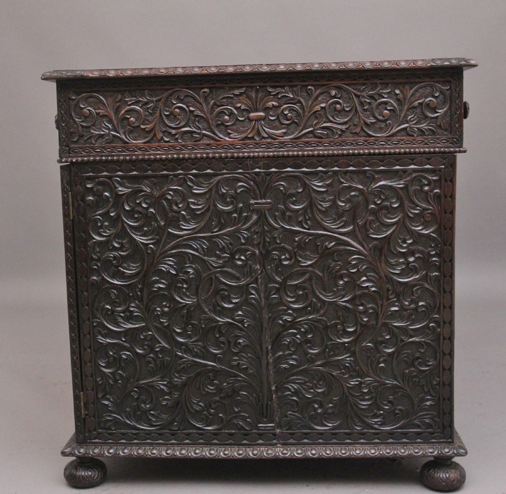 A dark wood double pedestal partners desk featuring intricate relief floral carvings across all drawers, side panels, and top borders. View III