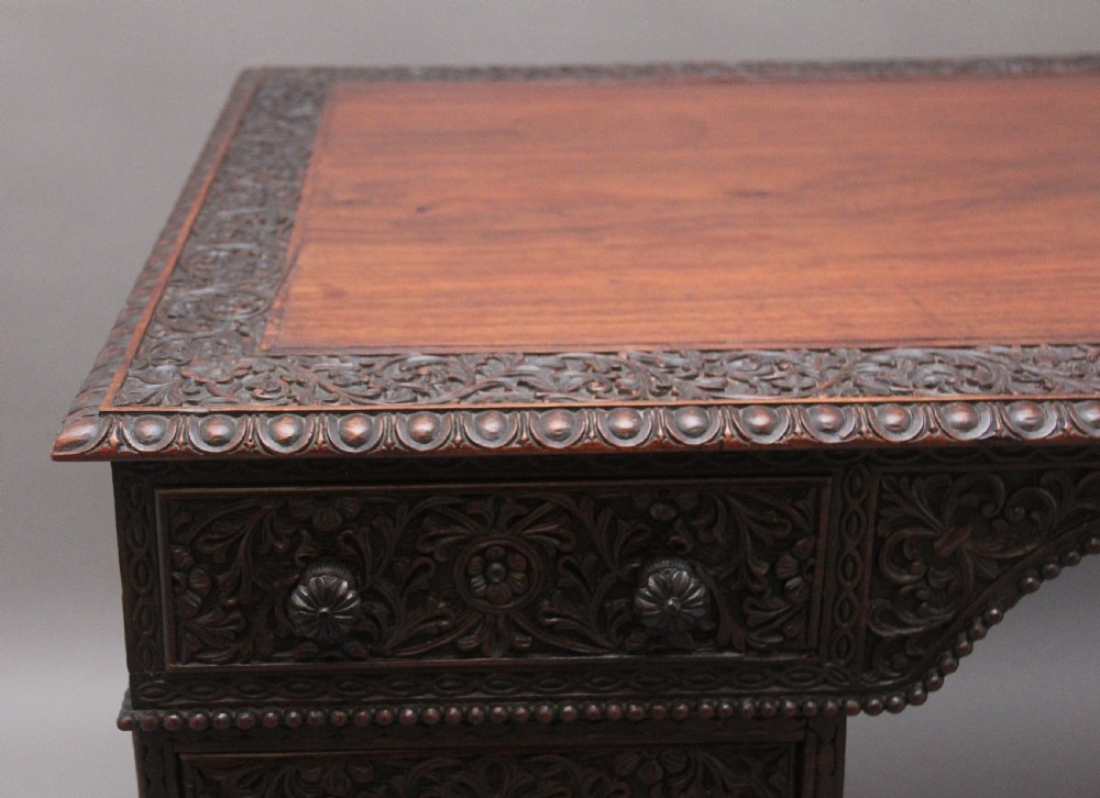 A dark wood double pedestal partners desk featuring intricate relief floral carvings across all drawers, side panels, and top borders. View XII