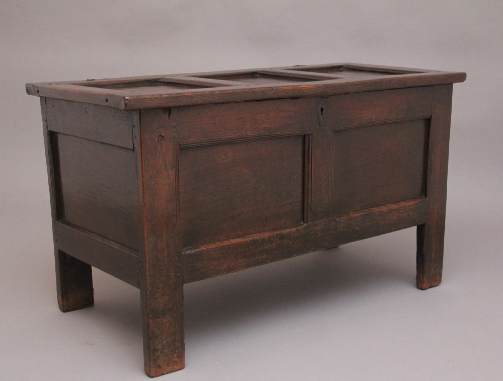 An 18th-century dark oak coffer featuring a three-panel hinged top, twin-panelled front, central keyhole escutcheon, and sturdy stile legs. View II