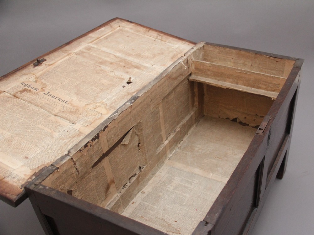 An 18th-century dark oak coffer featuring a three-panel hinged top, twin-panelled front, central keyhole escutcheon, and sturdy stile legs. View IV