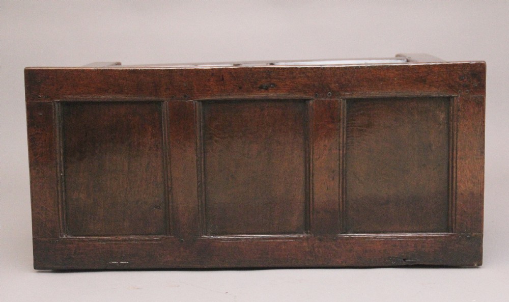 An 18th-century dark oak coffer featuring a three-panel hinged top, twin-panelled front, central keyhole escutcheon, and sturdy stile legs. View VIII