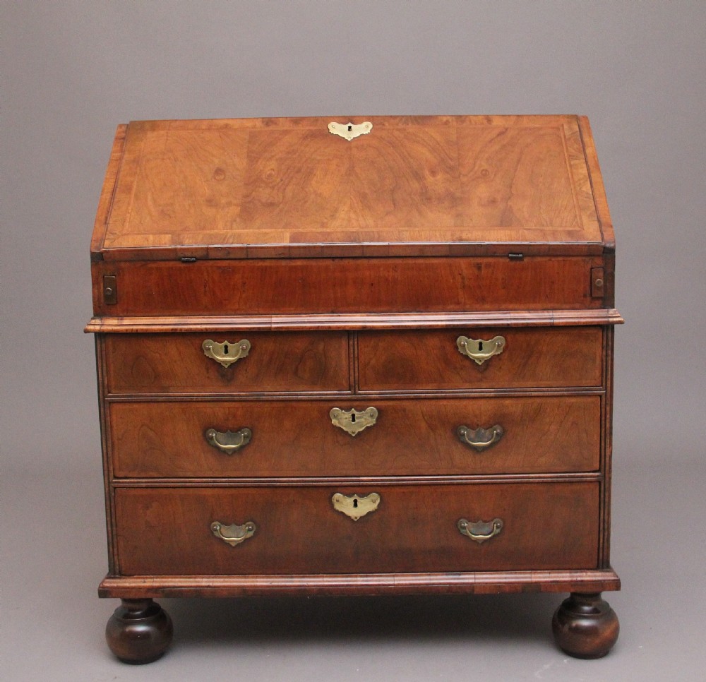 An 18th century walnut writing bureau featuring a sloped fall-front lid, brass drop handles, keyhole escutcheons, and turned ball feet. View II