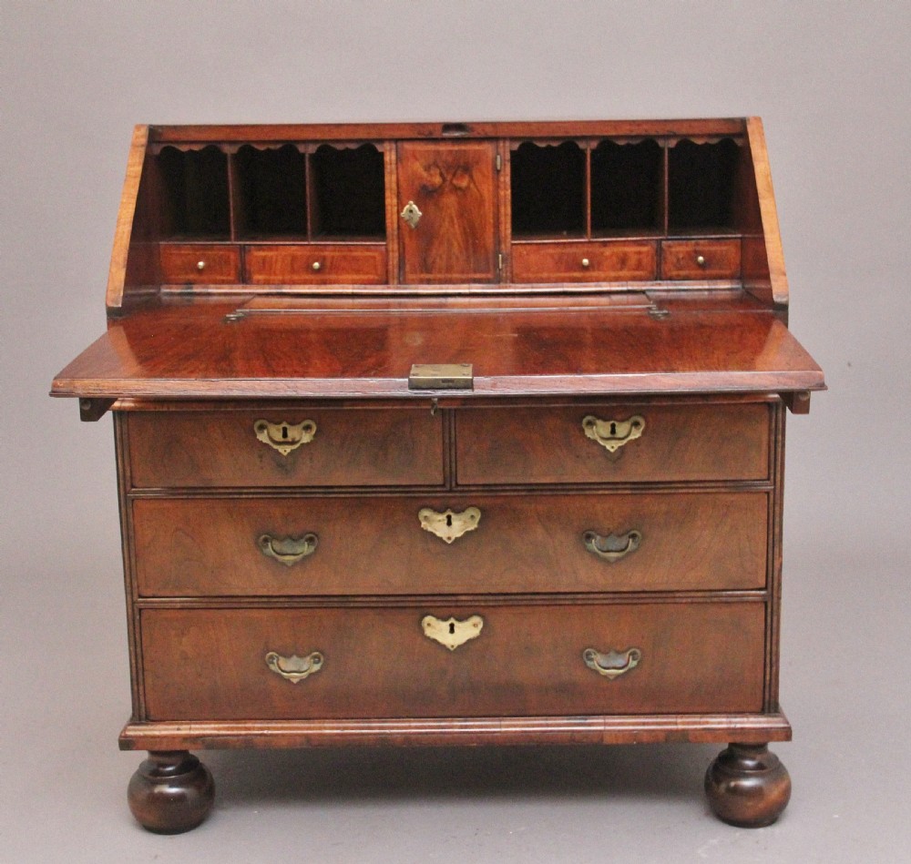 An 18th century walnut writing bureau featuring a sloped fall-front lid, brass drop handles, keyhole escutcheons, and turned ball feet. View III