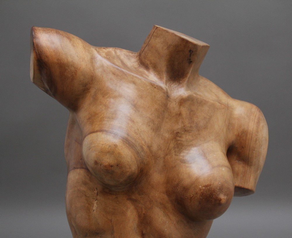 A life-size carved wooden female torso sculpture displayed against a neutral grey background. View VII