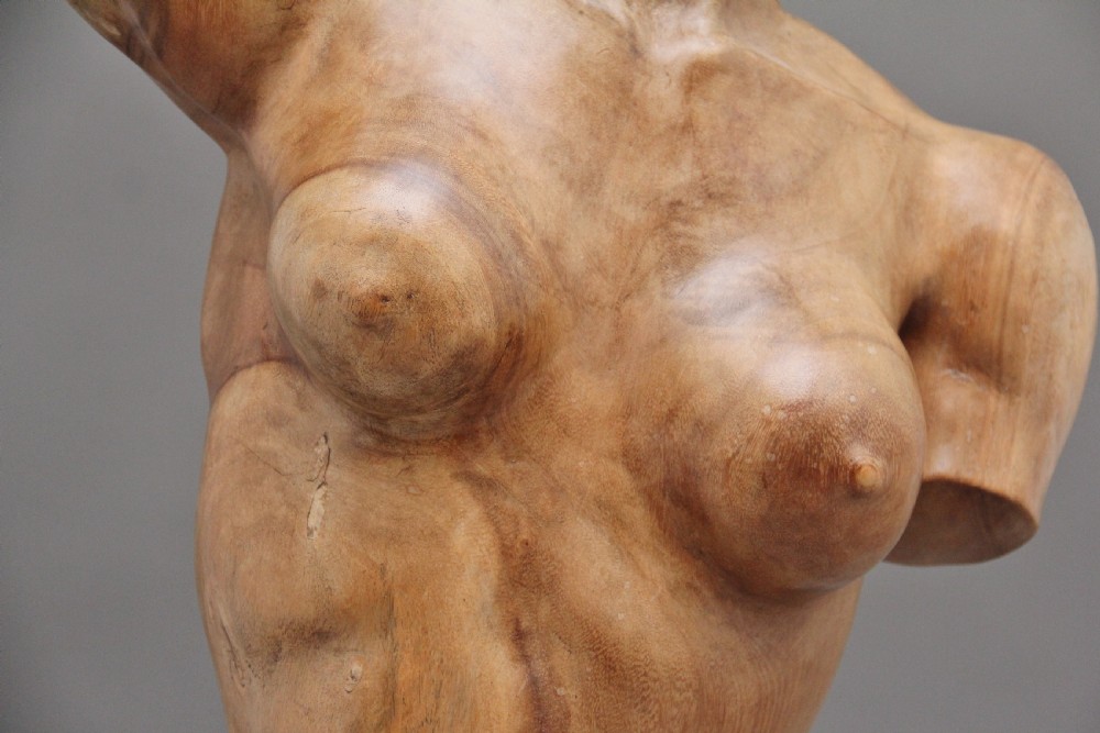 A life-size carved wooden female torso sculpture displayed against a neutral grey background. View XI