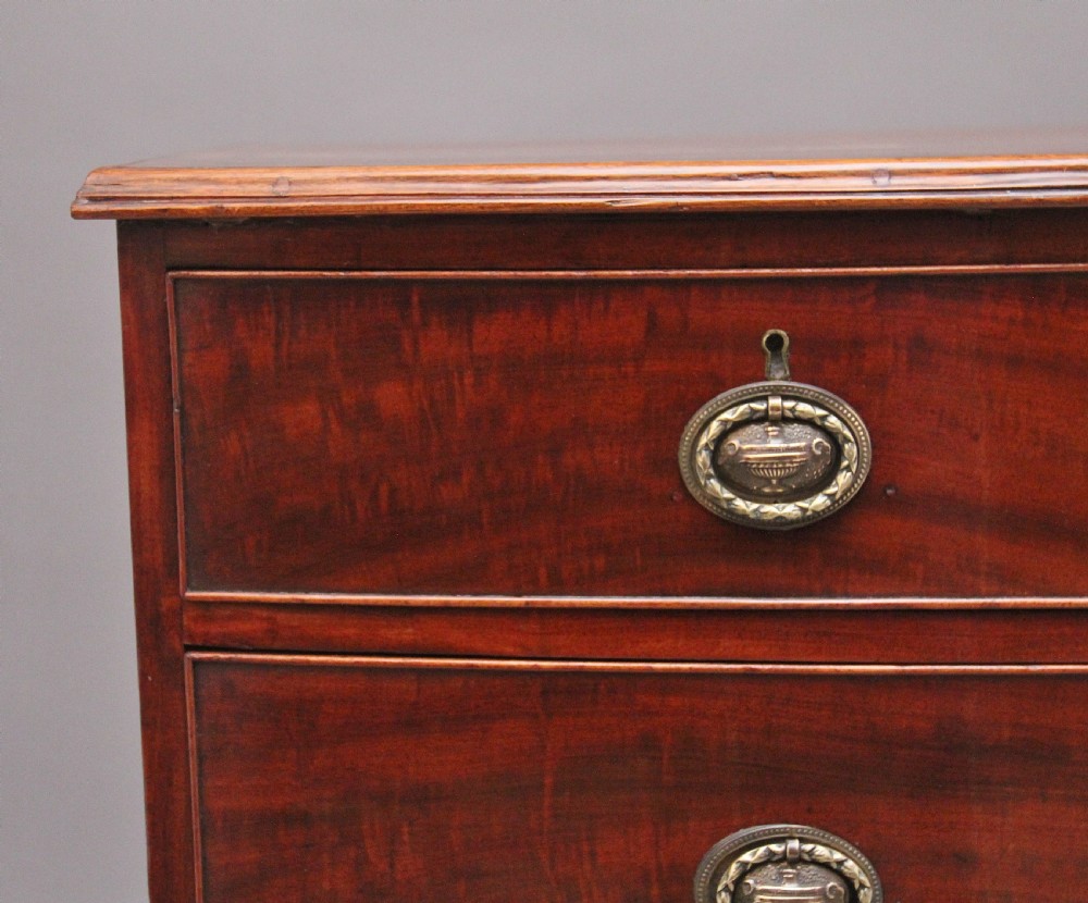 An early nineteenth-century mahogany bowfront chest of drawers featuring two short drawers over three long drawers with brass oval handles and bracket feet. View III