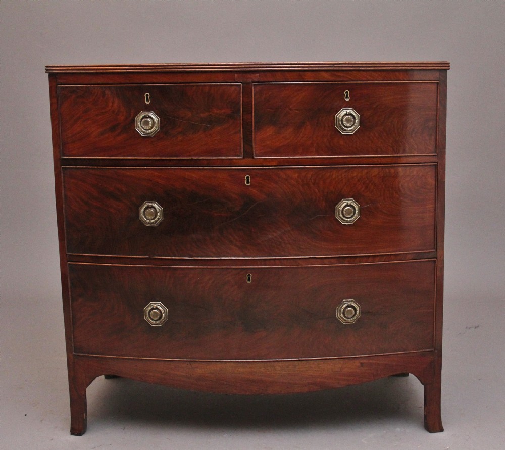 An early nineteenth-century flame mahogany bowfront chest of drawers featuring a two over two drawer configuration with brass octagonal ring handles.