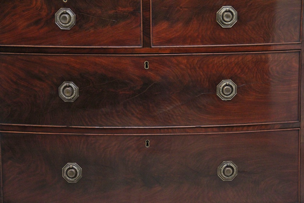 An early nineteenth-century flame mahogany bowfront chest of drawers featuring a two over two drawer configuration with brass octagonal ring handles. View II