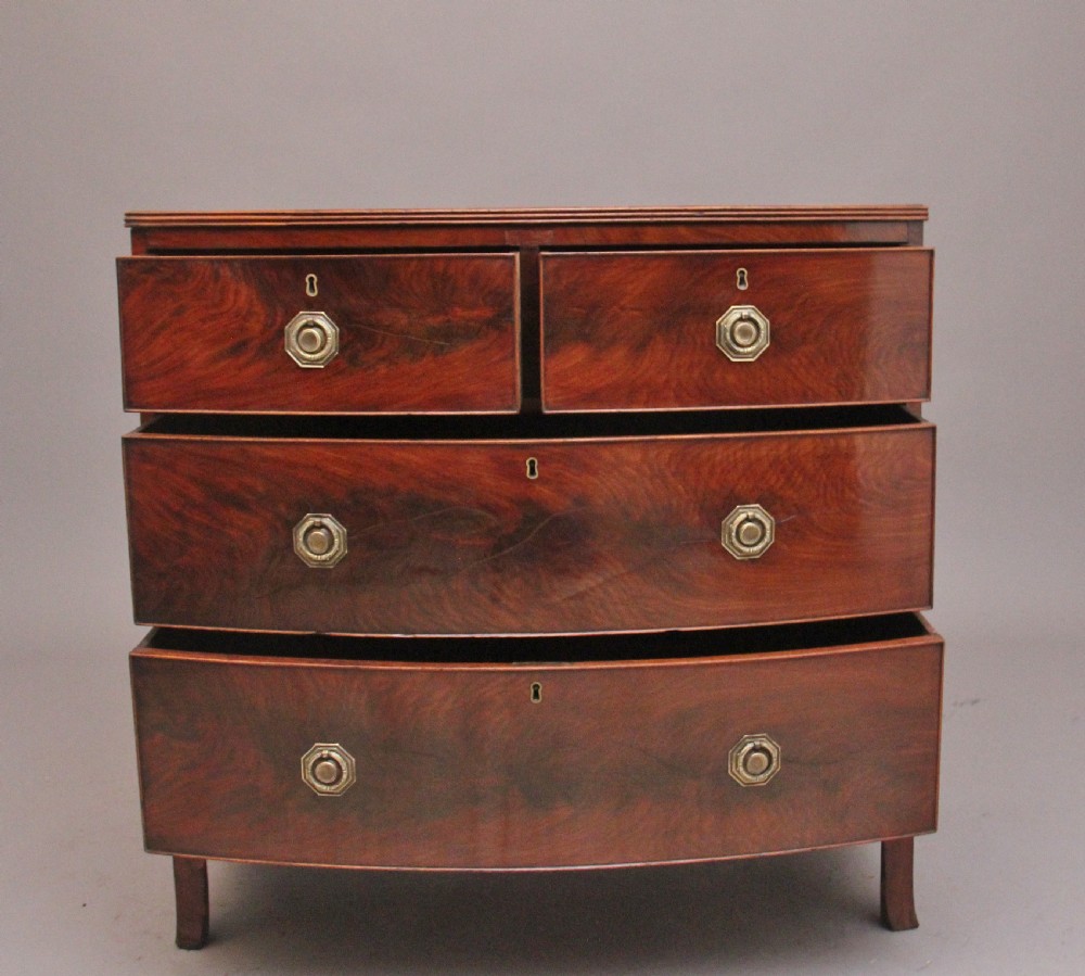 An early nineteenth-century flame mahogany bowfront chest of drawers featuring a two over two drawer configuration with brass octagonal ring handles. View IV
