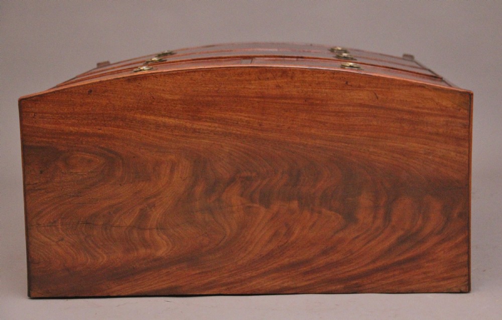 An early nineteenth-century flame mahogany bowfront chest of drawers featuring a two over two drawer configuration with brass octagonal ring handles. View XI