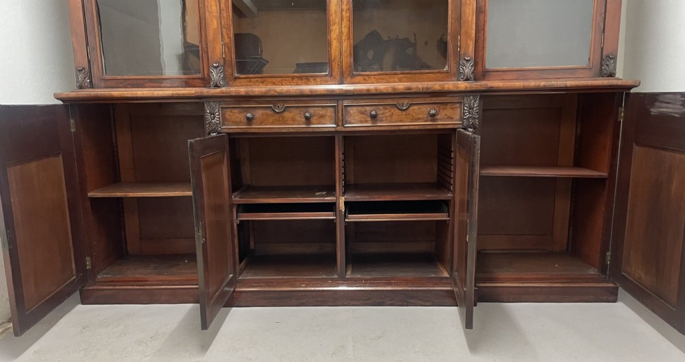 An early 19th-century dark mahogany breakfront bookcase featuring a four-door glazed upper section above four cupboard doors and drawers. View IV