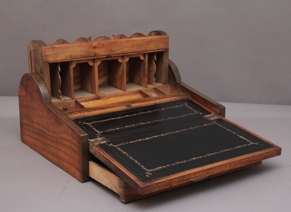 A 19th-century camphor wood writing slope featuring brass-bound corners, a sloped front, a tambour roll-top section, and a central brass inlay plate. View II