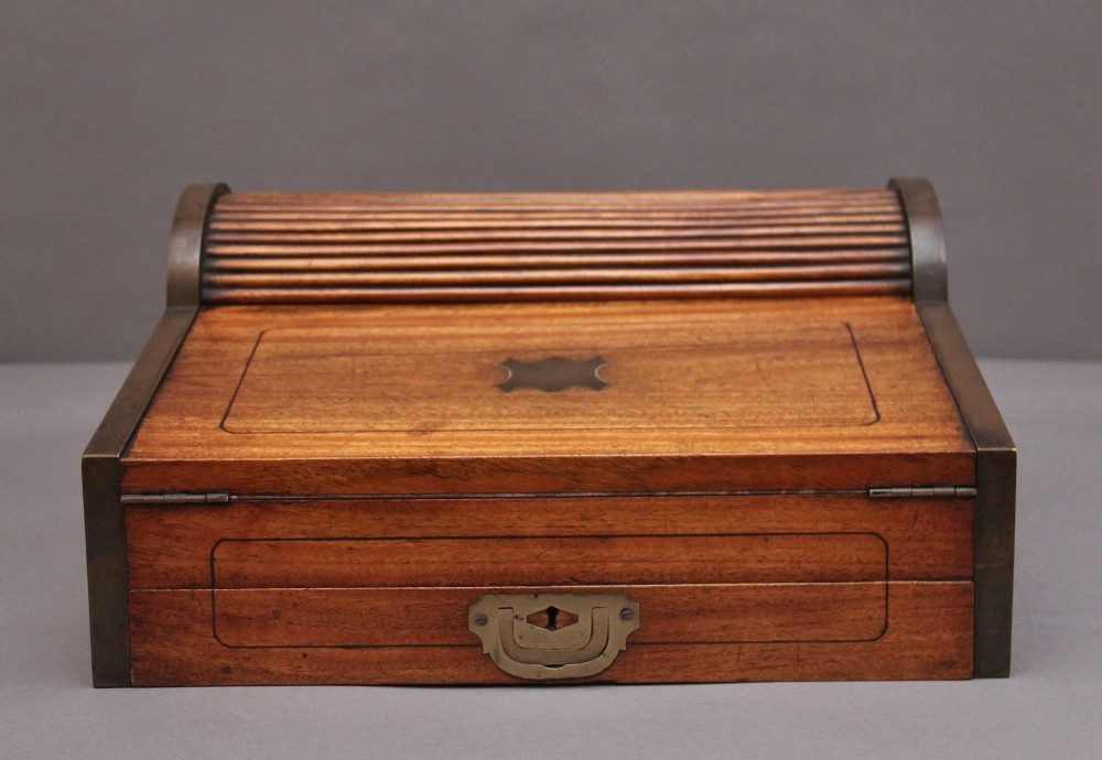 A 19th-century camphor wood writing slope featuring brass-bound corners, a sloped front, a tambour roll-top section, and a central brass inlay plate. View III
