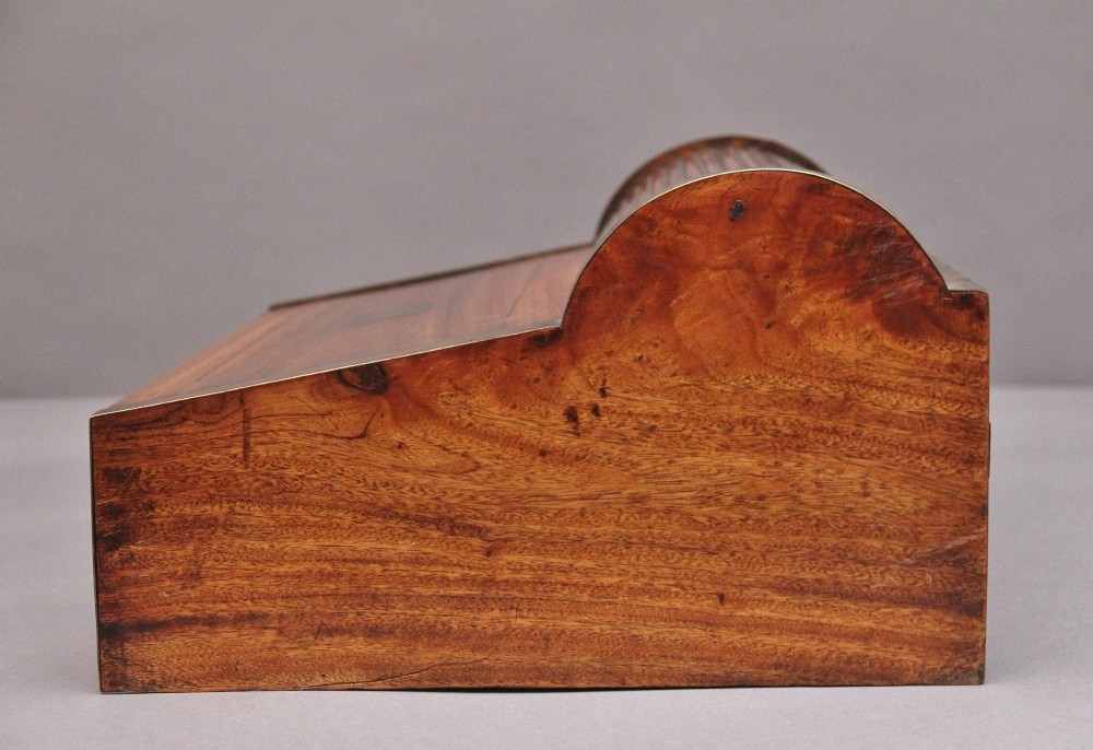 A 19th-century camphor wood writing slope featuring brass-bound corners, a sloped front, a tambour roll-top section, and a central brass inlay plate. View VIII