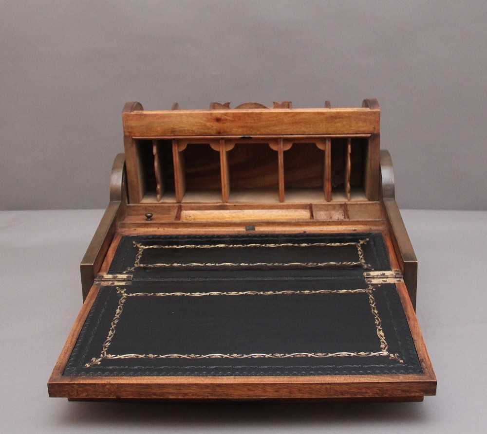 A 19th-century camphor wood writing slope featuring brass-bound corners, a sloped front, a tambour roll-top section, and a central brass inlay plate. View XI