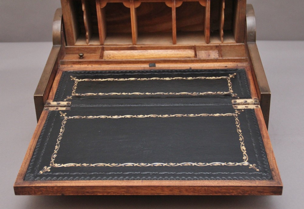 A 19th-century camphor wood writing slope featuring brass-bound corners, a sloped front, a tambour roll-top section, and a central brass inlay plate. View XII
