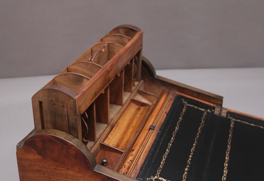 A 19th-century camphor wood writing slope featuring brass-bound corners, a sloped front, a tambour roll-top section, and a central brass inlay plate. View XIII