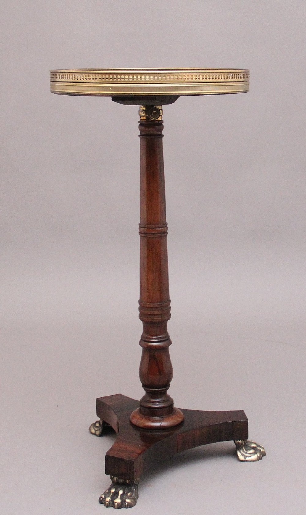 A 19th-century dark rosewood telescopic occasional table with a circular top featuring a brass gallery rim, a turned pedestal column, and a triform base on brass claw feet.
