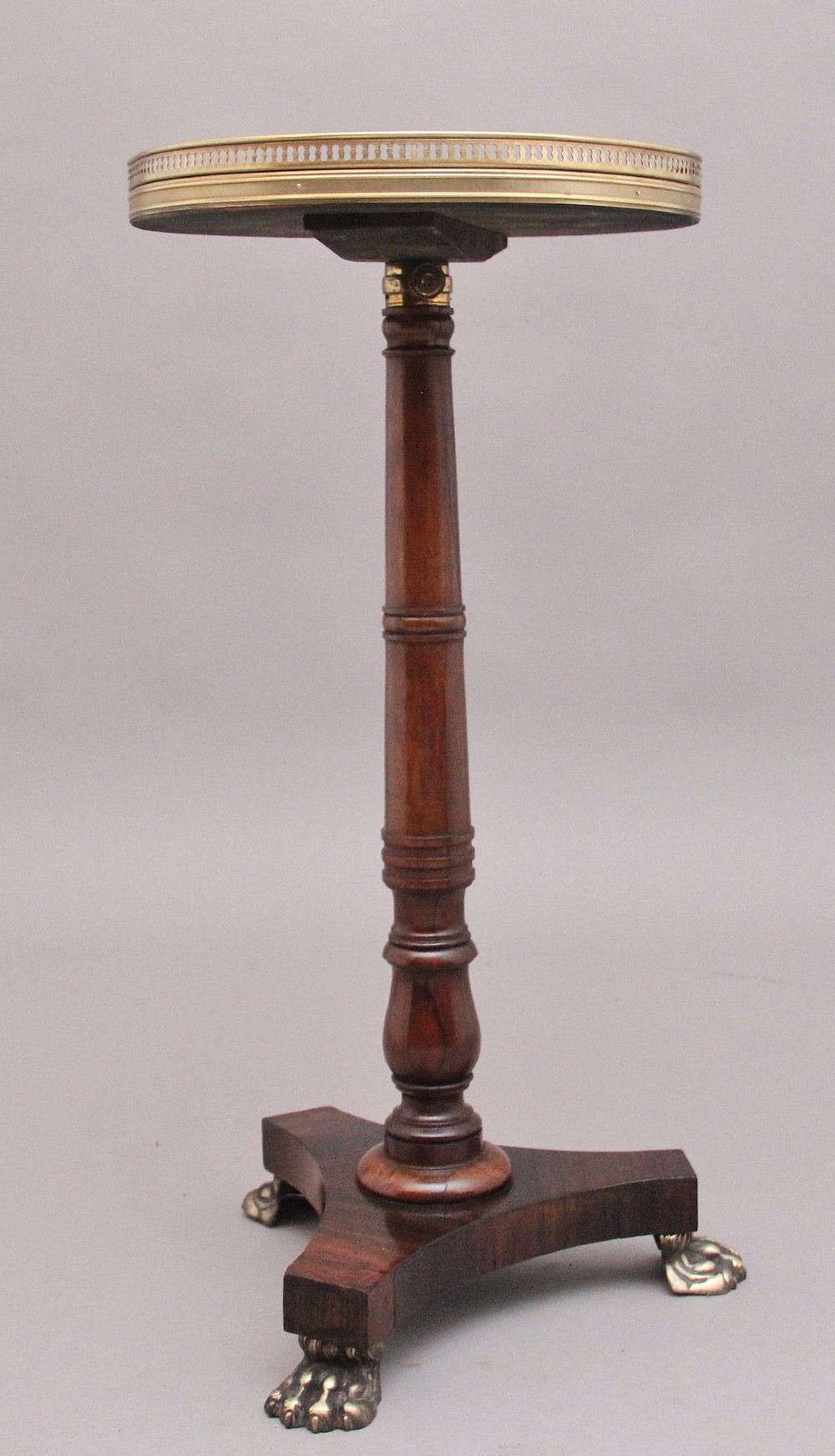 A 19th-century dark rosewood telescopic occasional table with a circular top featuring a brass gallery rim, a turned pedestal column, and a triform base on brass claw feet. View II