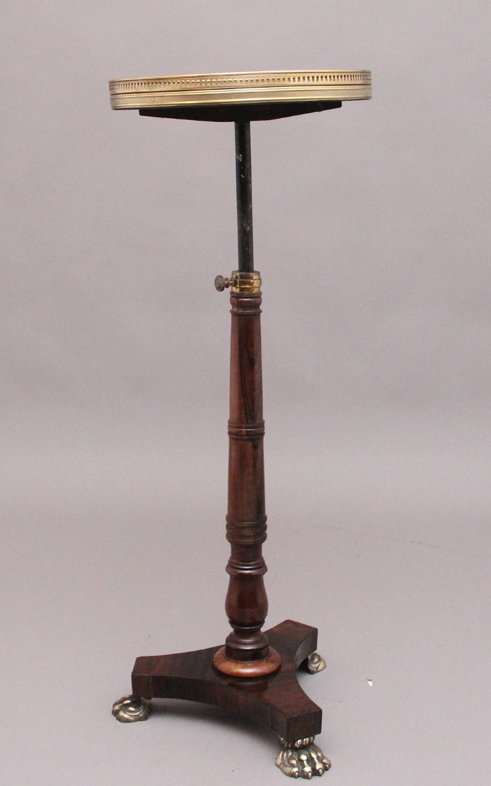 A 19th-century dark rosewood telescopic occasional table with a circular top featuring a brass gallery rim, a turned pedestal column, and a triform base on brass claw feet. View IV