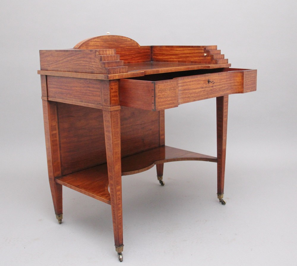 A 19th-century satinwood ladies writing table featuring a stepped side gallery, single frieze drawer, tapered square legs on brass castors, and a lower undertier. View II