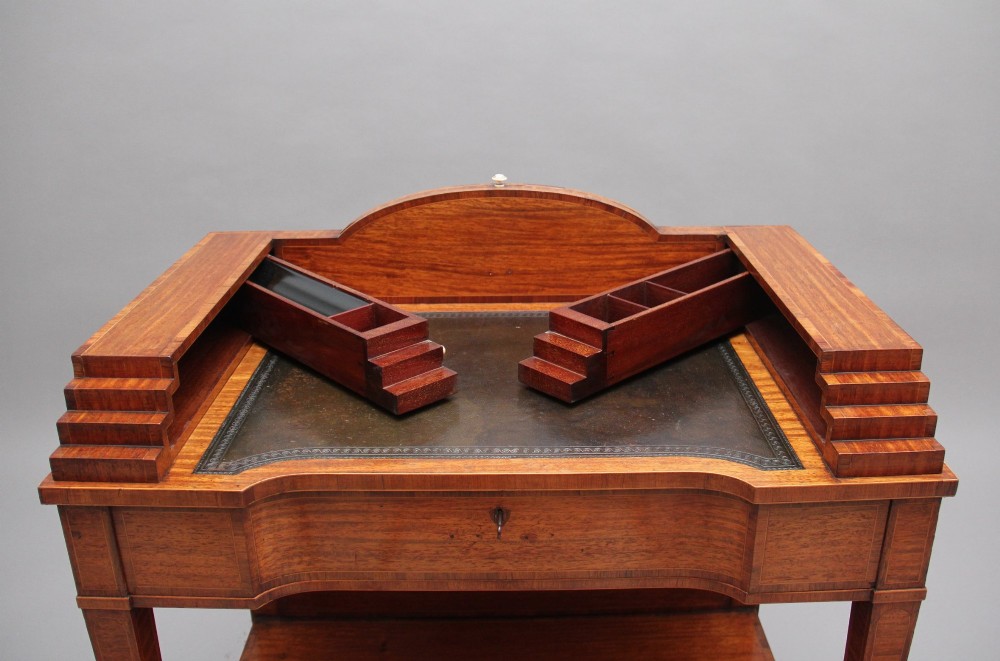 A 19th-century satinwood ladies writing table featuring a stepped side gallery, single frieze drawer, tapered square legs on brass castors, and a lower undertier. View IV