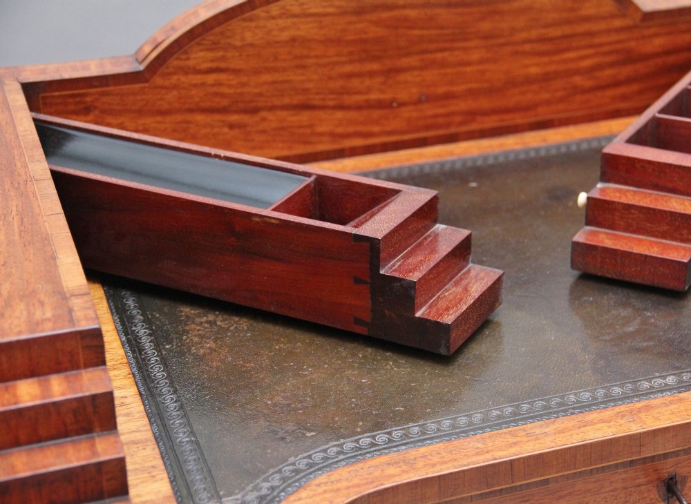 A 19th-century satinwood ladies writing table featuring a stepped side gallery, single frieze drawer, tapered square legs on brass castors, and a lower undertier. View V