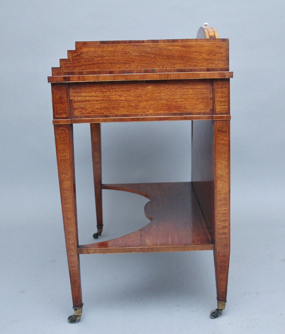 A 19th-century satinwood ladies writing table featuring a stepped side gallery, single frieze drawer, tapered square legs on brass castors, and a lower undertier. View X