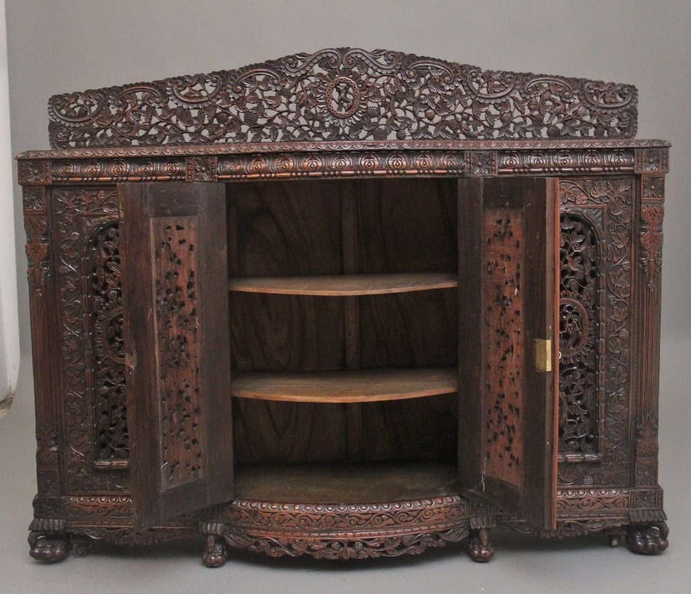 A 19th-century Anglo-Indian dark wood cabinet featuring elaborate pierced foliage carvings, four cupboard doors, and a decorative carved gallery back. View III