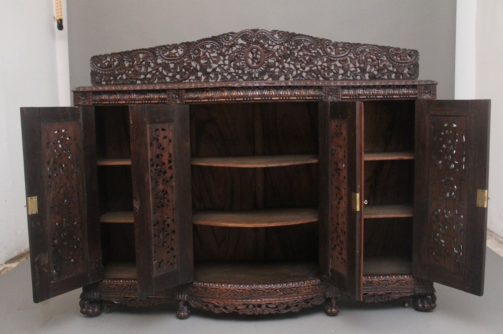 A 19th-century Anglo-Indian dark wood cabinet featuring elaborate pierced foliage carvings, four cupboard doors, and a decorative carved gallery back. View IV