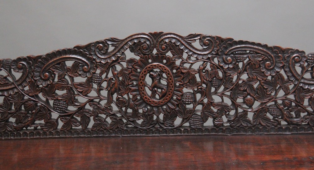 A 19th-century Anglo-Indian dark wood cabinet featuring elaborate pierced foliage carvings, four cupboard doors, and a decorative carved gallery back. View VIII