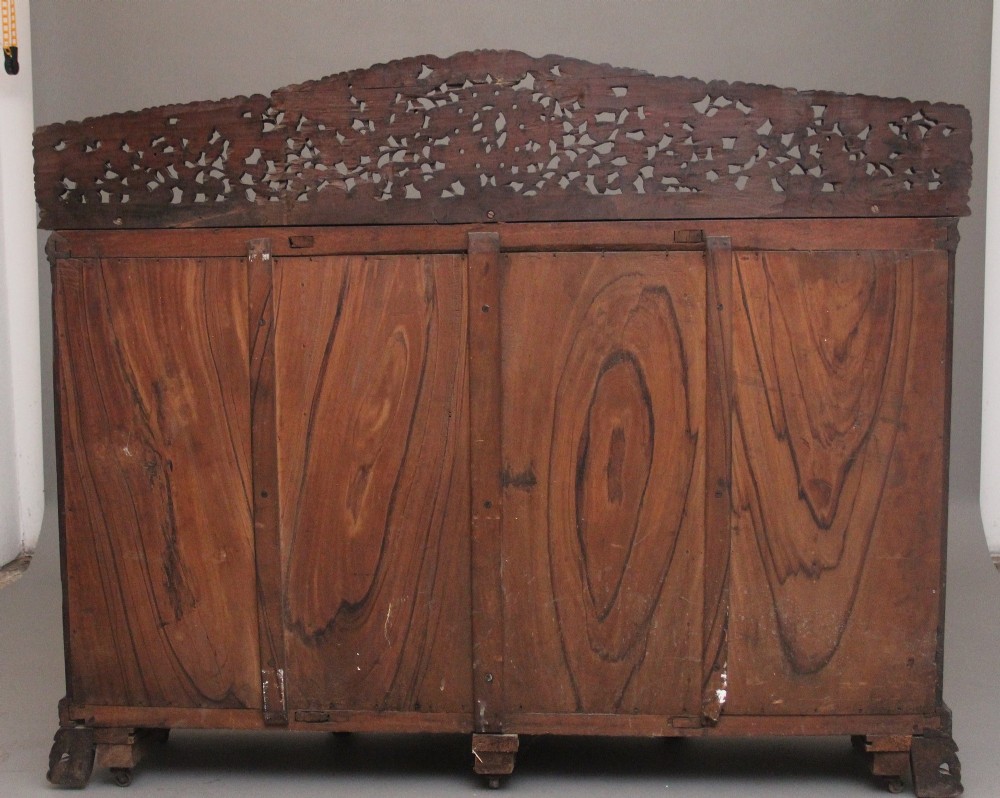 A 19th-century Anglo-Indian dark wood cabinet featuring elaborate pierced foliage carvings, four cupboard doors, and a decorative carved gallery back. View X