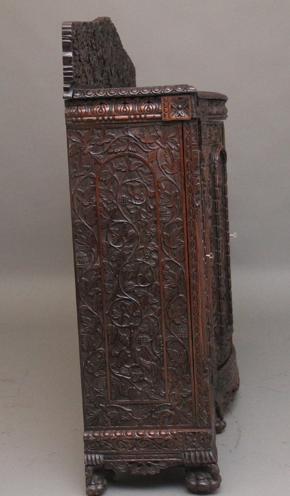 A 19th-century Anglo-Indian dark wood cabinet featuring elaborate pierced foliage carvings, four cupboard doors, and a decorative carved gallery back. View XI