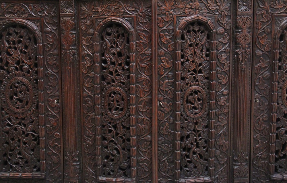 A 19th-century Anglo-Indian dark wood cabinet featuring elaborate pierced foliage carvings, four cupboard doors, and a decorative carved gallery back. View XII