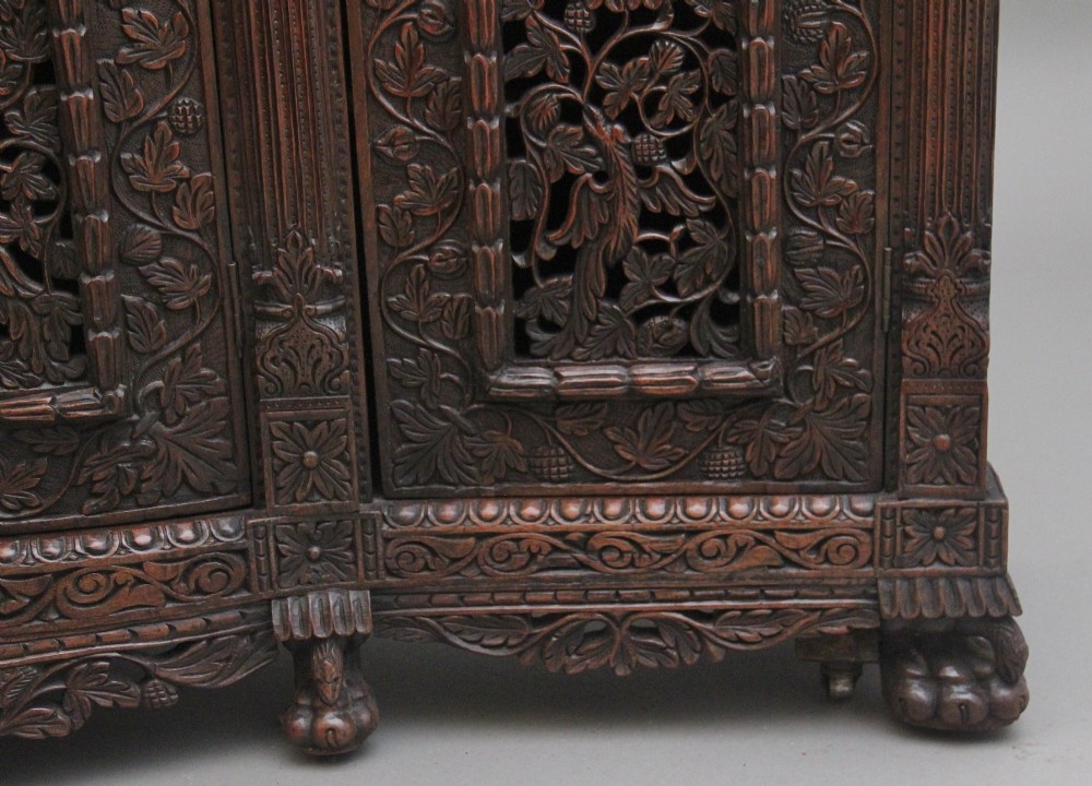 A 19th-century Anglo-Indian dark wood cabinet featuring elaborate pierced foliage carvings, four cupboard doors, and a decorative carved gallery back. View XIV